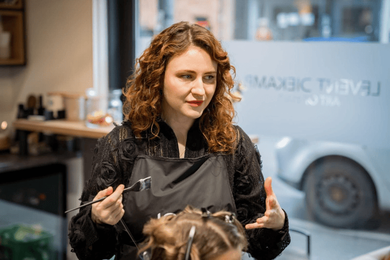 Anna bei der Balayage und Foilyage im Friseursalon Levent Diekamp Köln Coloristin im Friseursalon trägt mit Pinsel eine Balayage- bzw. Foilyage-Farbe auf das Haar einer Kundin auf, professionelle Haarfärbetechnik in Köln.