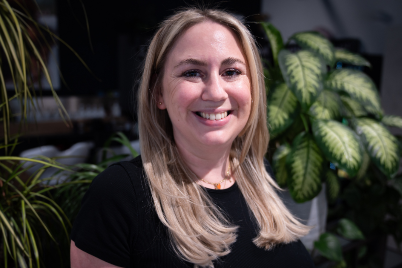 Eine strahlende Friseurmeisterin vor Pflanzen in einem Salon